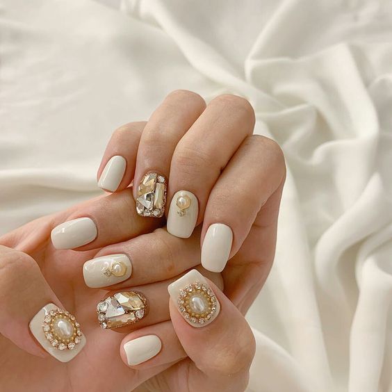 Mẫu nail trong suốt pha chút sắc hồng, nhấn nhá 1 phần nail bằng sơn trắng và nhũ vàng
