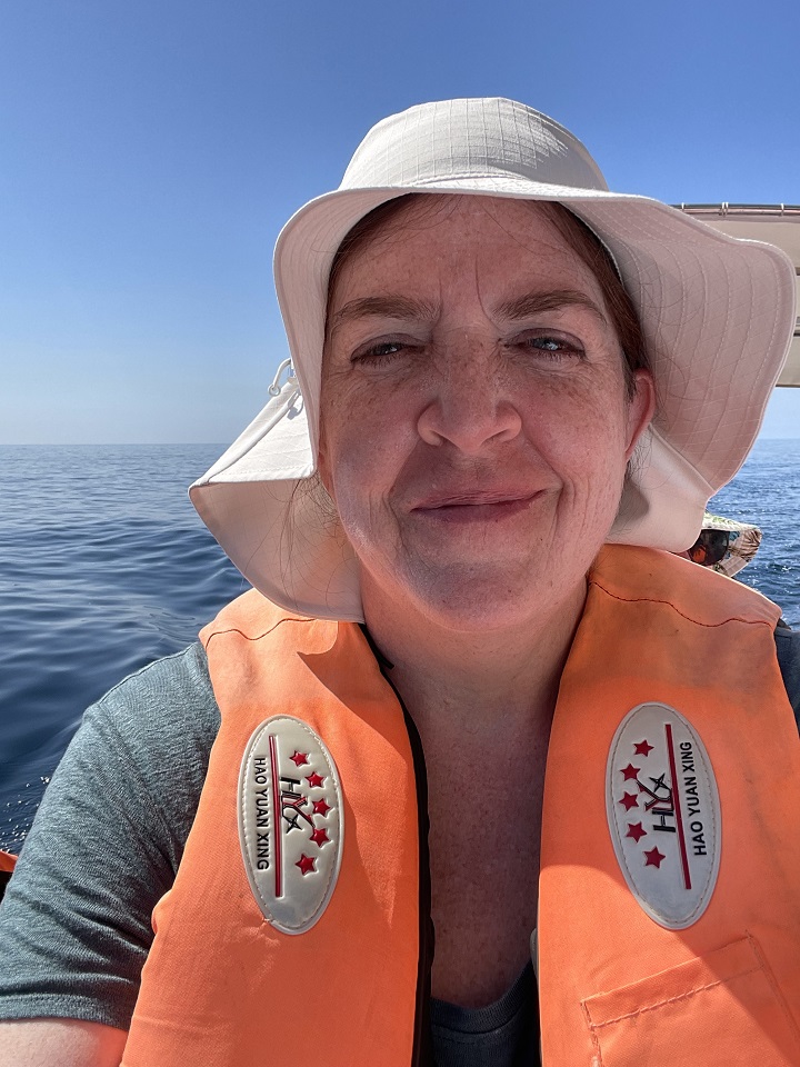 Philatravelgirl with tan hat and orange life vest sitting in a boat touring Malta