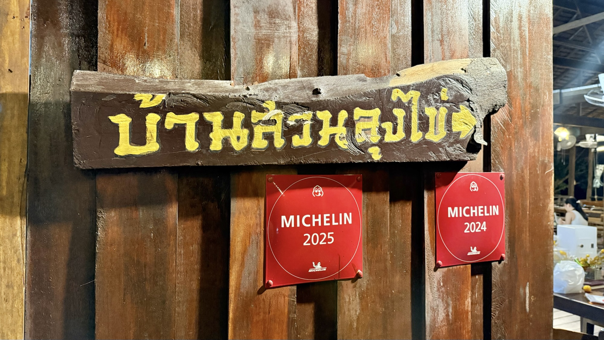 A wooden sign with Thai writing indicating