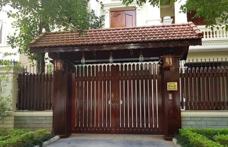 Trụ cổng và cổng gỗ lim với các thanh gỗ dọc và mau vừa tăng tính thẩm mỹ, vừa bảo vệ tốt cho căn biệt thự.