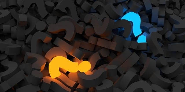 A blue and yellow question mark surrounded by black question marks .