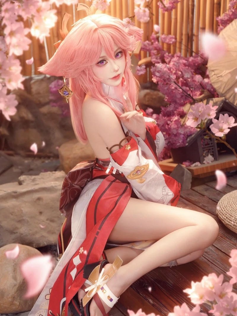 Yae miko cosplay ngồi giữa rừng hoa anh đào nở rộ