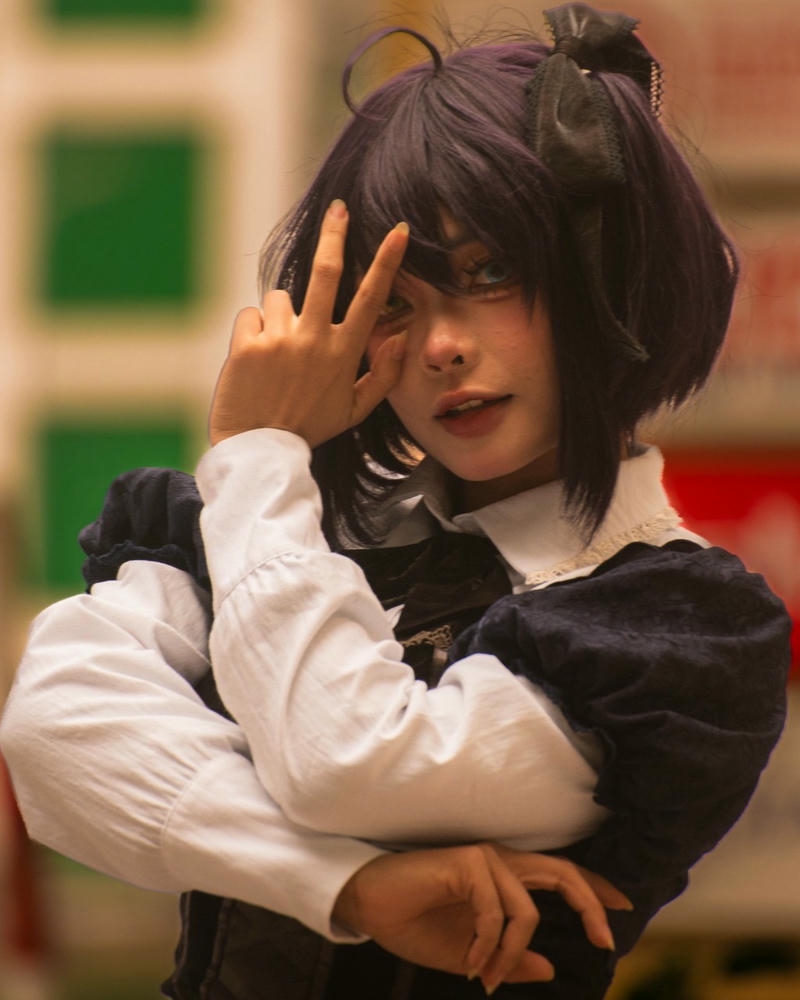 Cosplay anime nữ tóc đen đeo kính tạo dáng tay ngầu