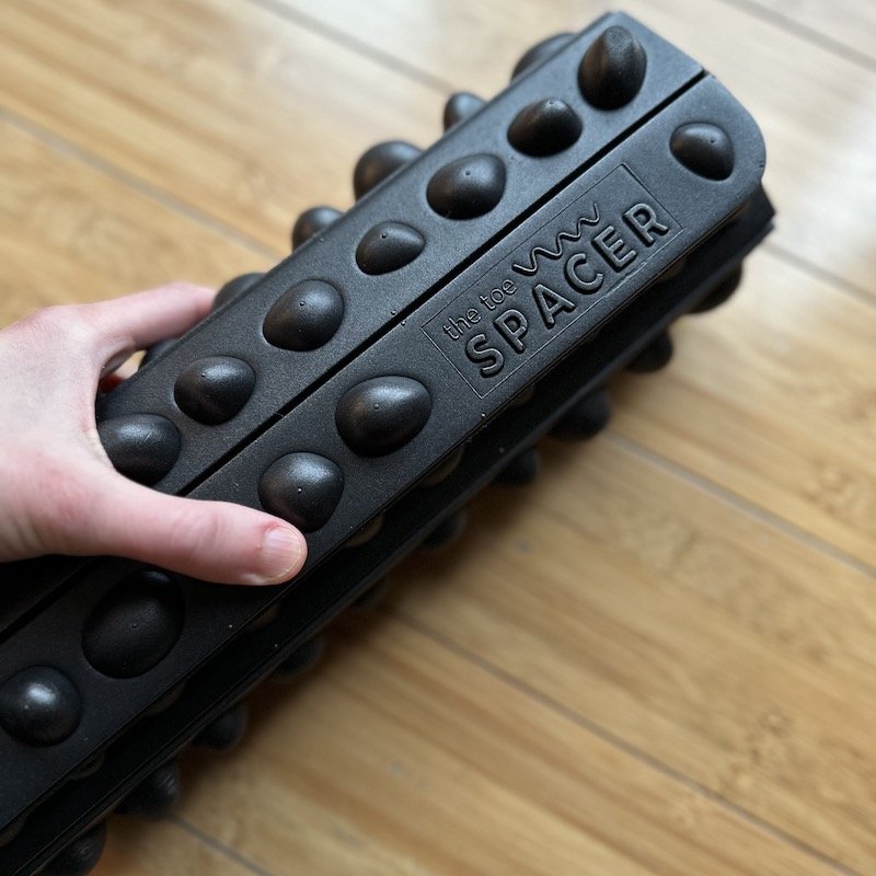 The Toe Spacer Rock Mat - a foam mat with rock-shaped bumps, rolled up for storage