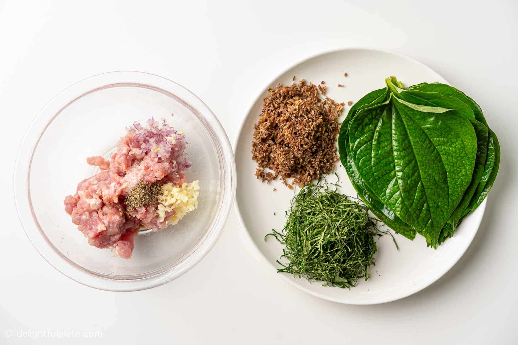 plates containing ingredients for Vietnamese pork rolls in wild betel leaves (cha la lot).