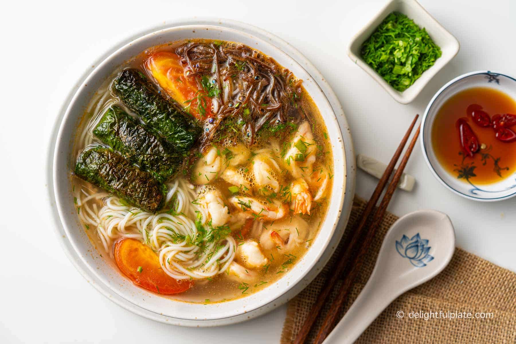 a bowl of Vietnamese shrimp noodle soup with pork in betel leaves cha la lot topping.