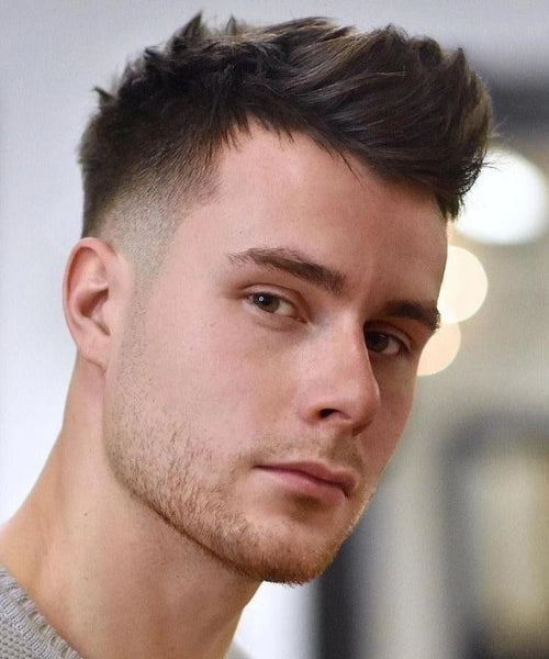 Medium quiff hairstyle with natural brushed-back volume and clean tapered sides.