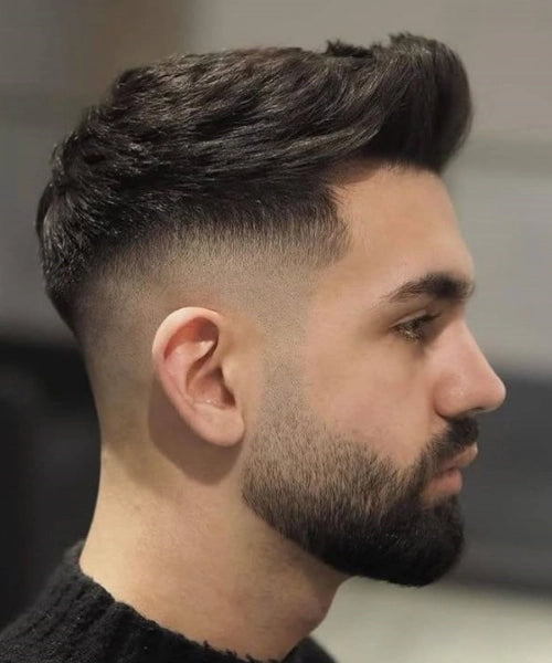 Modern quiff haircut with voluminous brushed-back top and sharp skin fade sides.