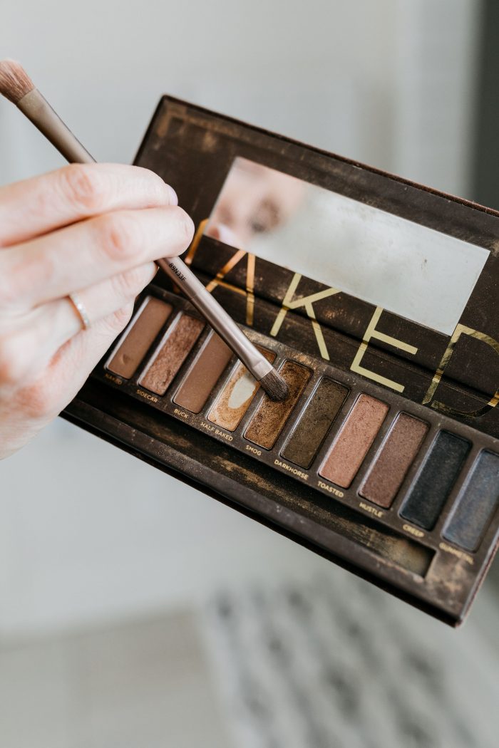 NAKED Palette Tutorial featured by top US beauty blog A Slice of Style; Image of woman in mustard sweater, applying eye shadow.