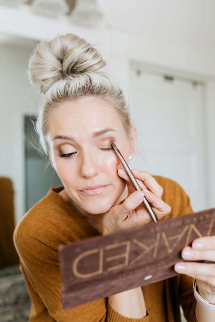 NAKED Palette Tutorial featured by top US beauty blog A Slice of Style; Image of woman in mustard sweater, applying eye shadow.