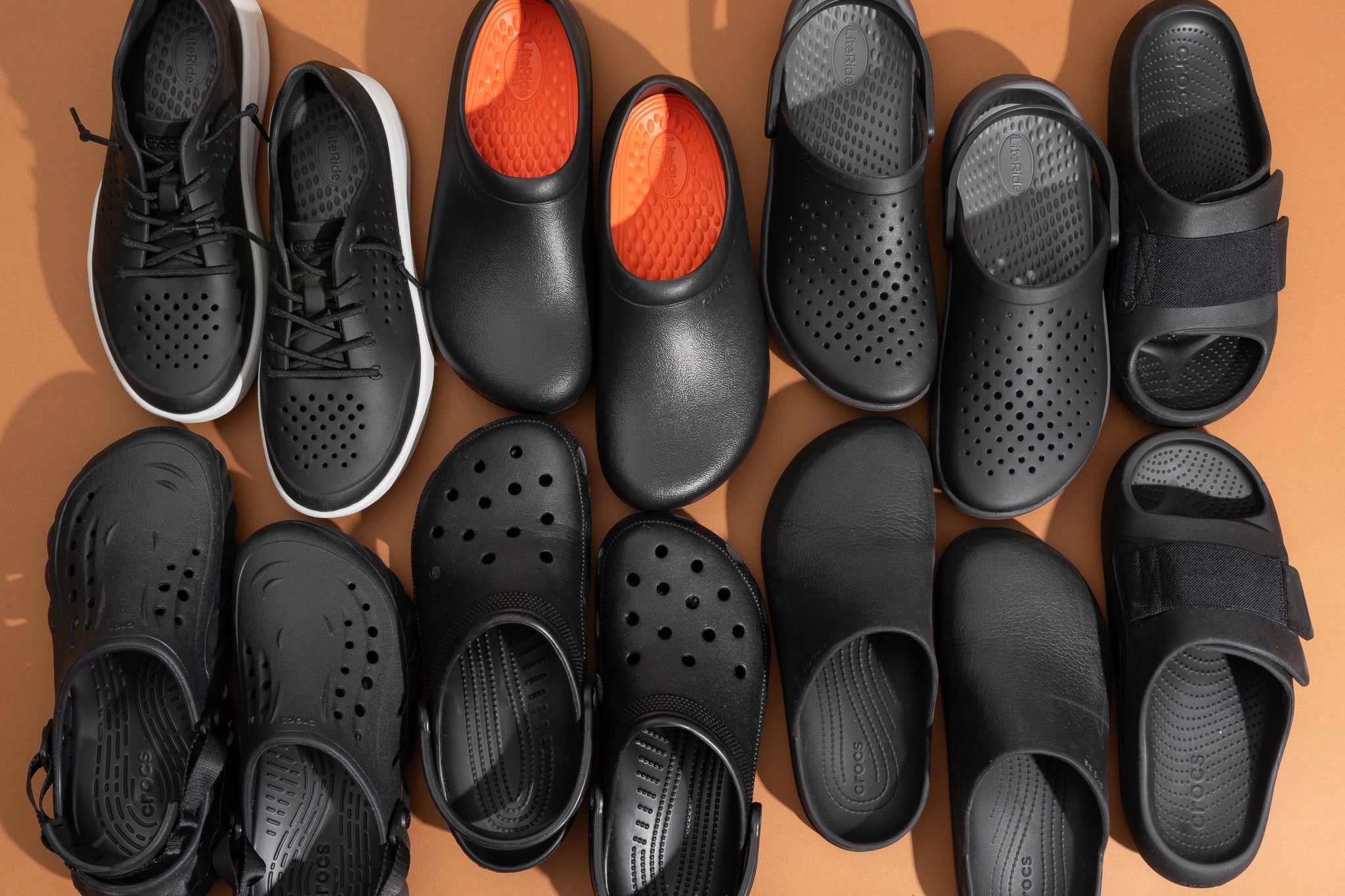 Various pairs of black Crocs lined up next to each other in two rows.
