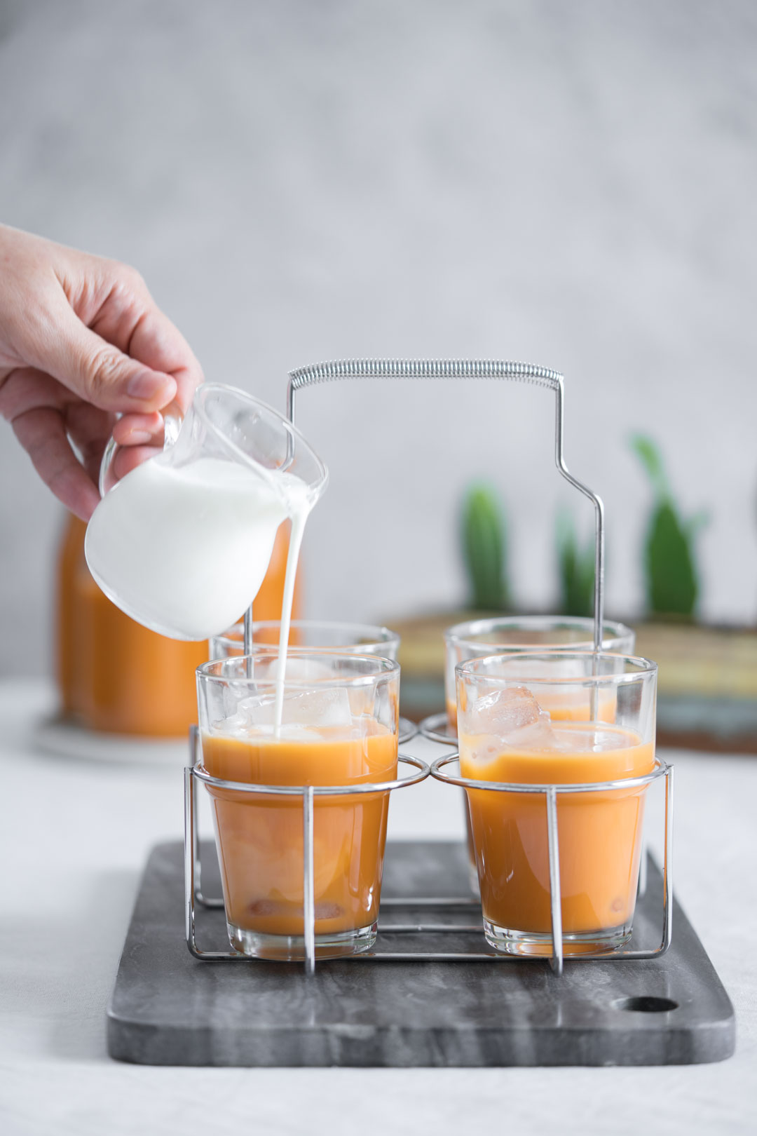 milk being poured over the top of a glass of Thai tea